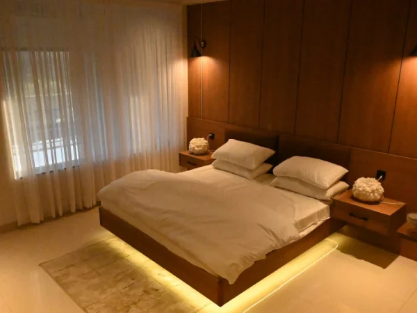 The Sultan Hotels luxury hotel room with warm LED lighting, wooden wall panels and white bedding in Islamabad